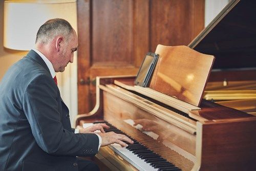 a man in a suit is playing a piano in a room .