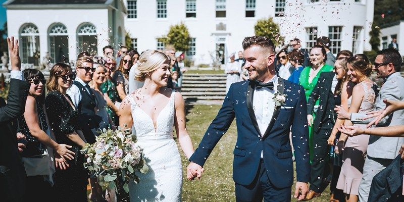 a bride and groom are walking through a crowd of people holding hands .