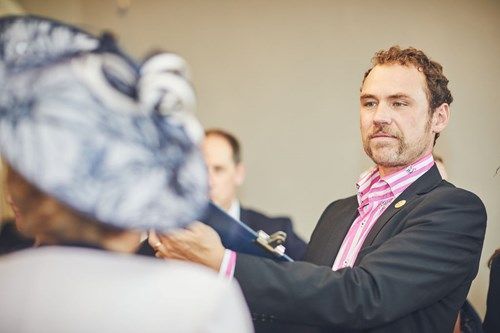 a man in a suit is talking to a woman in a hat .