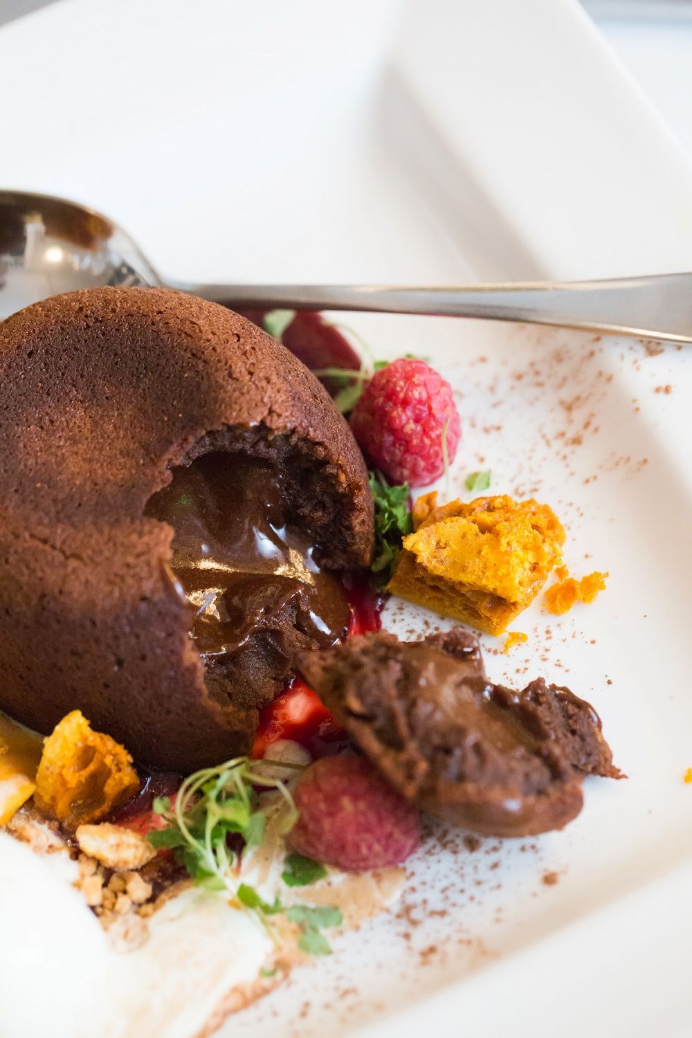a close up of a chocolate lava cake on a plate with strawberries and raspberries .