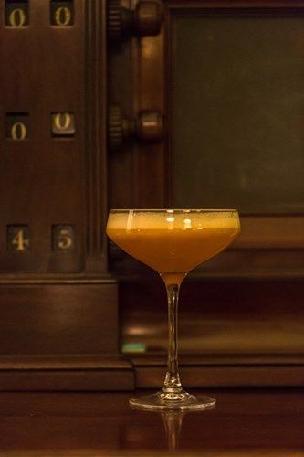 a glass of orange liquid is sitting on a wooden table .