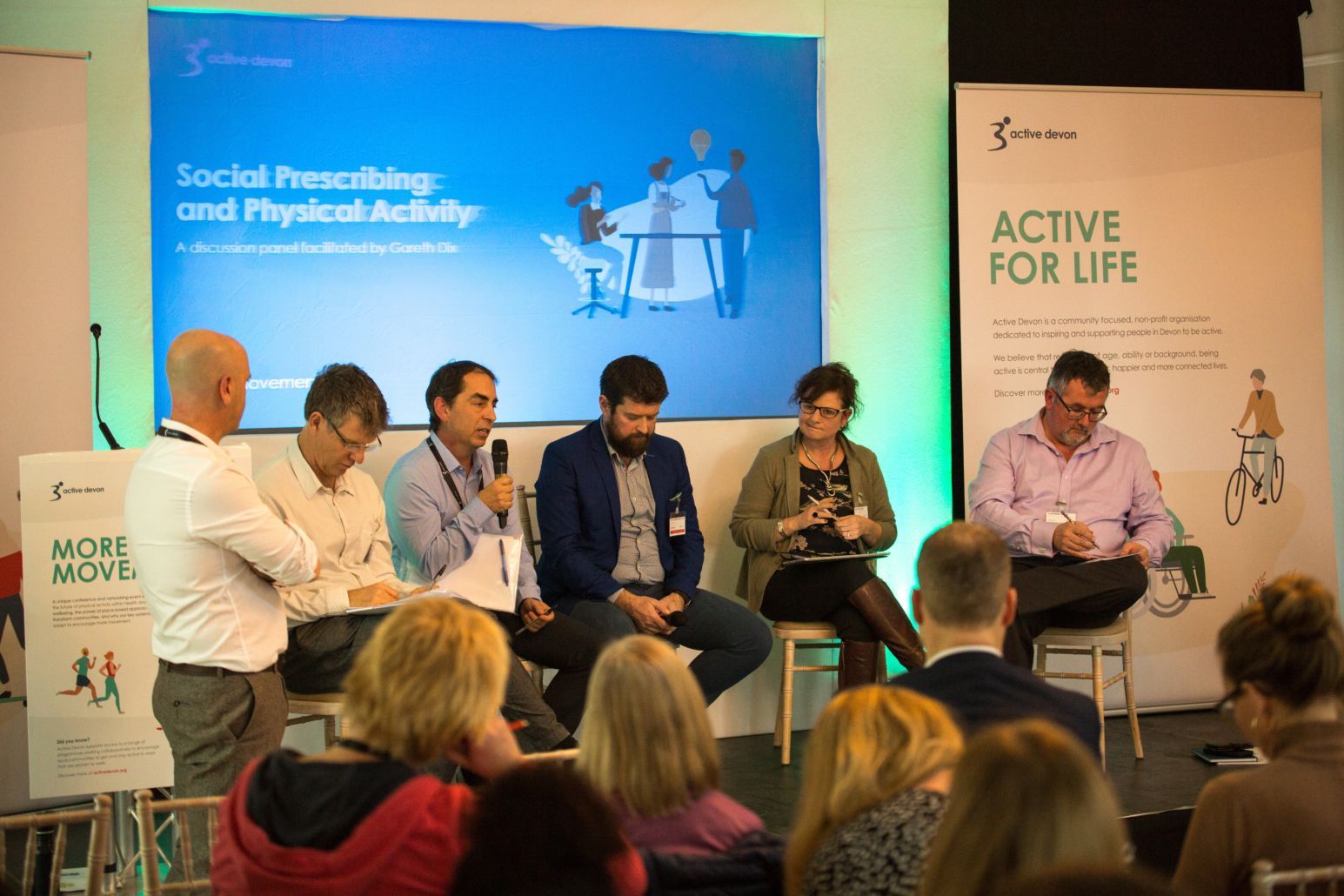 a group of people are sitting in front of a screen that says active for life .