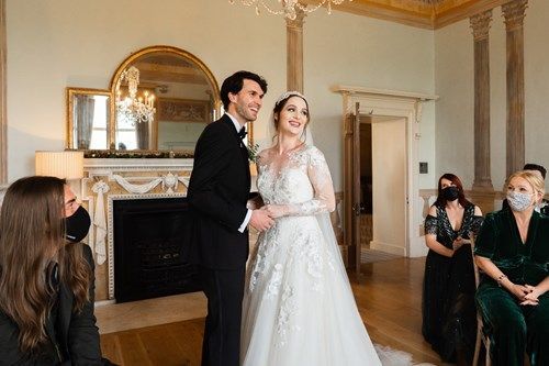a bride and groom are holding hands during their wedding ceremony in front of a fireplace .