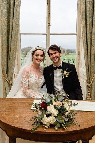 a bride and groom are sitting at a table in front of a window .