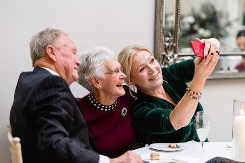 a woman is taking a selfie with her family at a table .