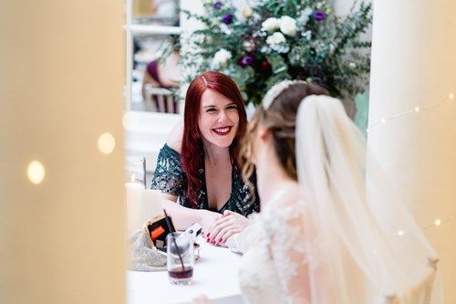 two women are sitting at a table talking to each other .