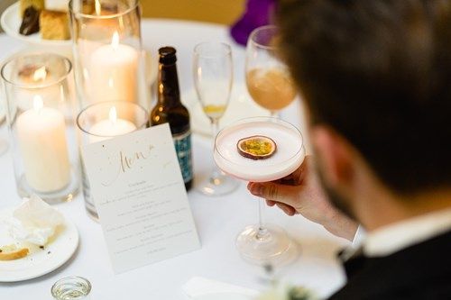 a man is holding a cocktail with a passion fruit on top of it .