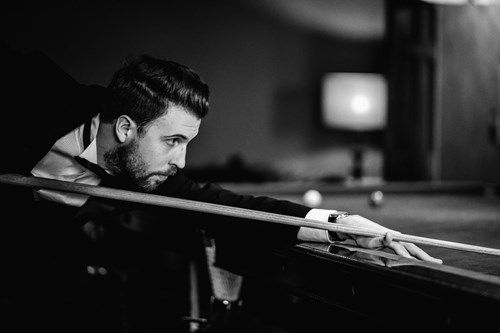 a man is playing pool in a black and white photo .