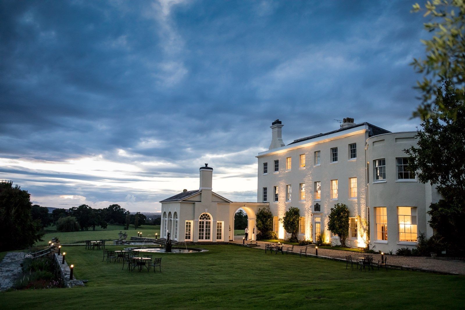 a large white house with a lot of windows is lit up at night .wedding venue in Exeter, Devon