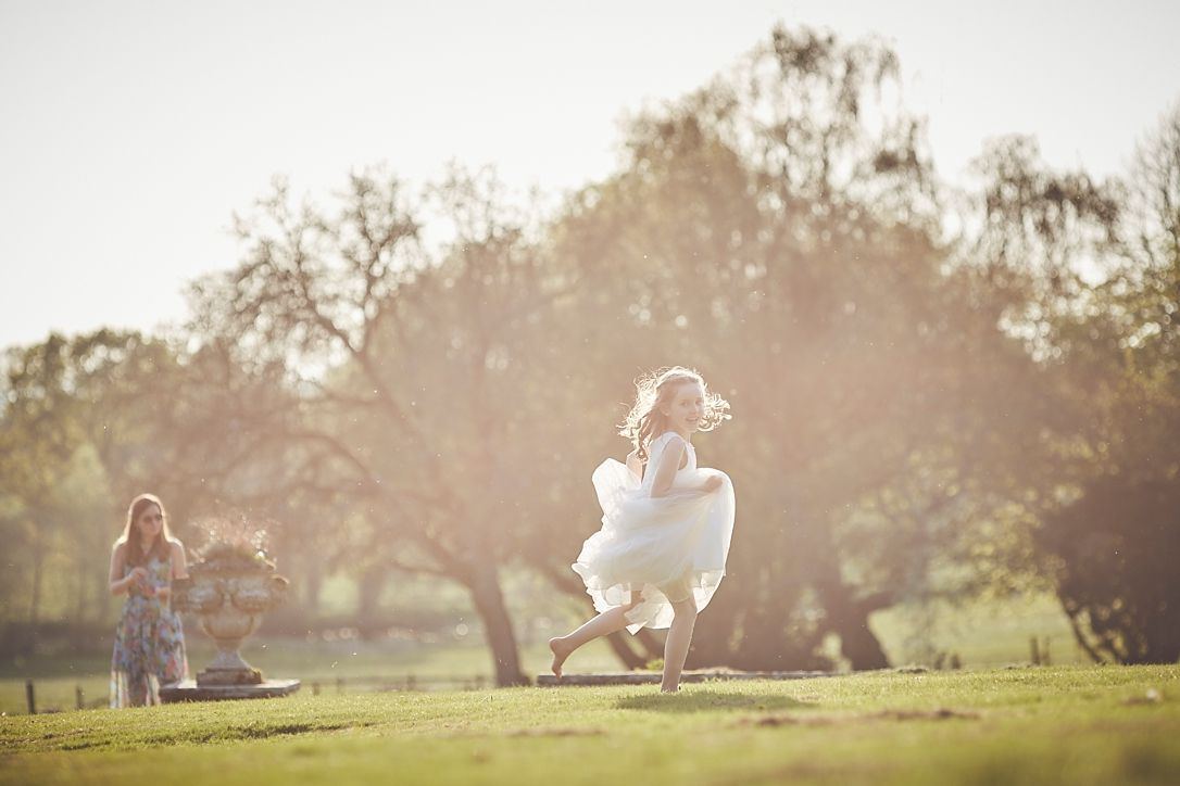a little girl in a white dress is running in a field .