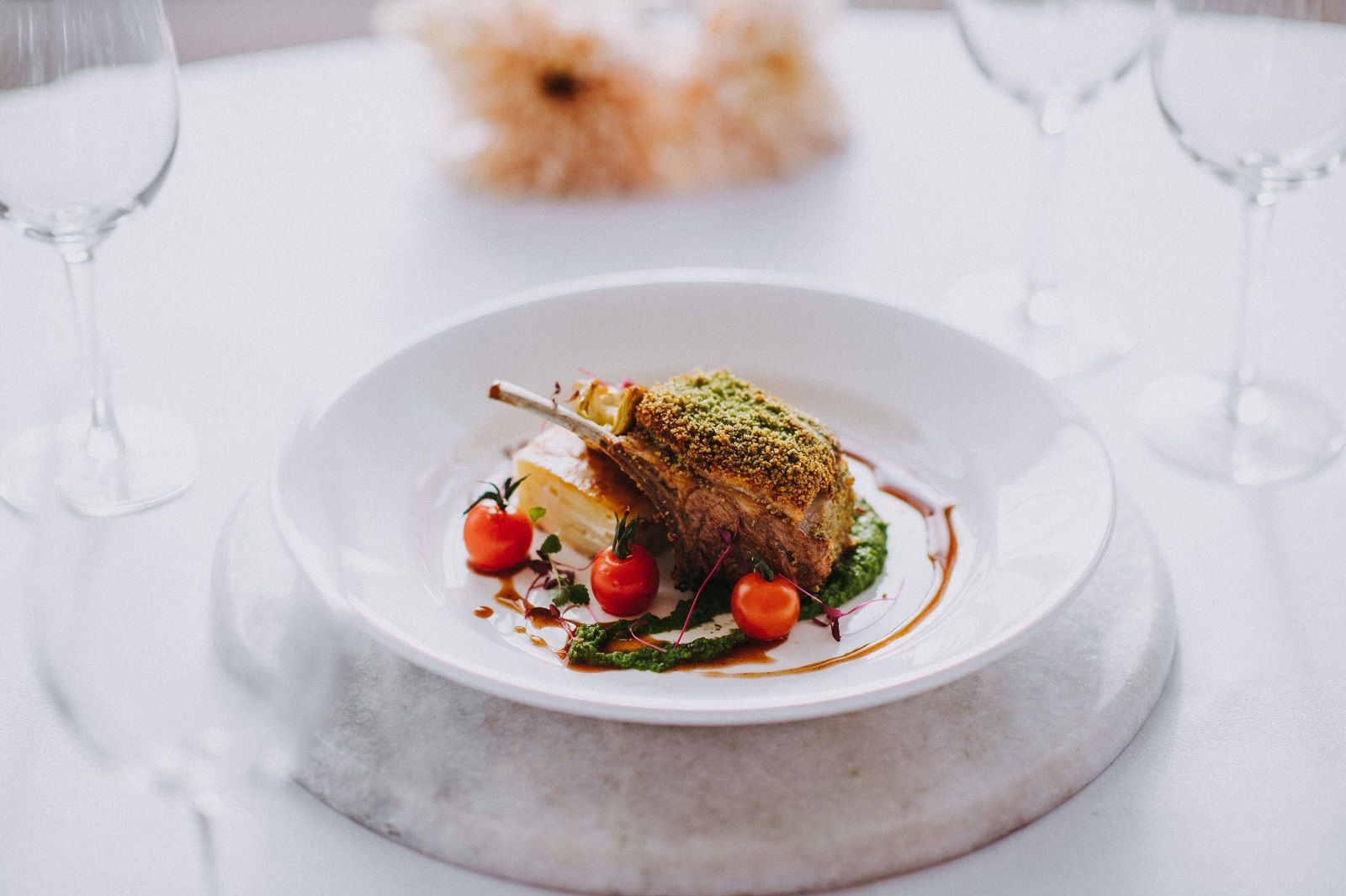 a white plate topped with a piece of meat and tomatoes on a table .
