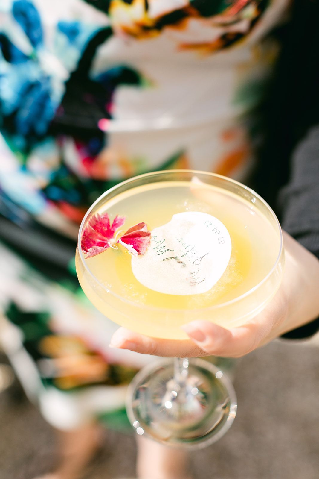 a person is holding a martini with a flower on top of it .