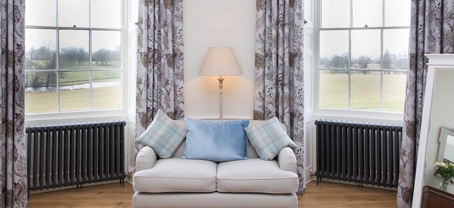 a living room with a couch , lamp , and curtains .