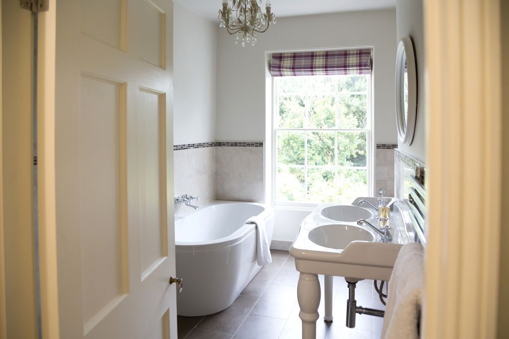 a bathroom with two sinks , a tub and a window .