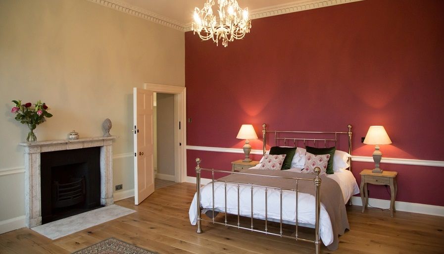 a bedroom with a bed , fireplace , lamps and a chandelier .