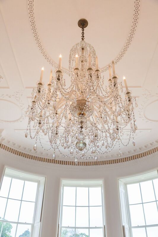 a large chandelier is hanging from the ceiling in a room with lots of windows .