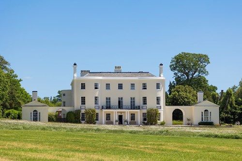 a large white house sits in the middle of a grassy field