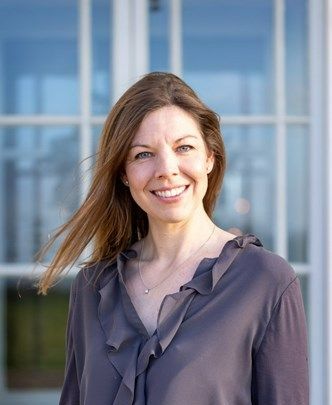 a woman in a ruffled blouse is smiling in front of a window .