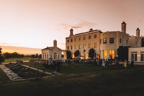 a group of people are standing in front of a large building at sunset .