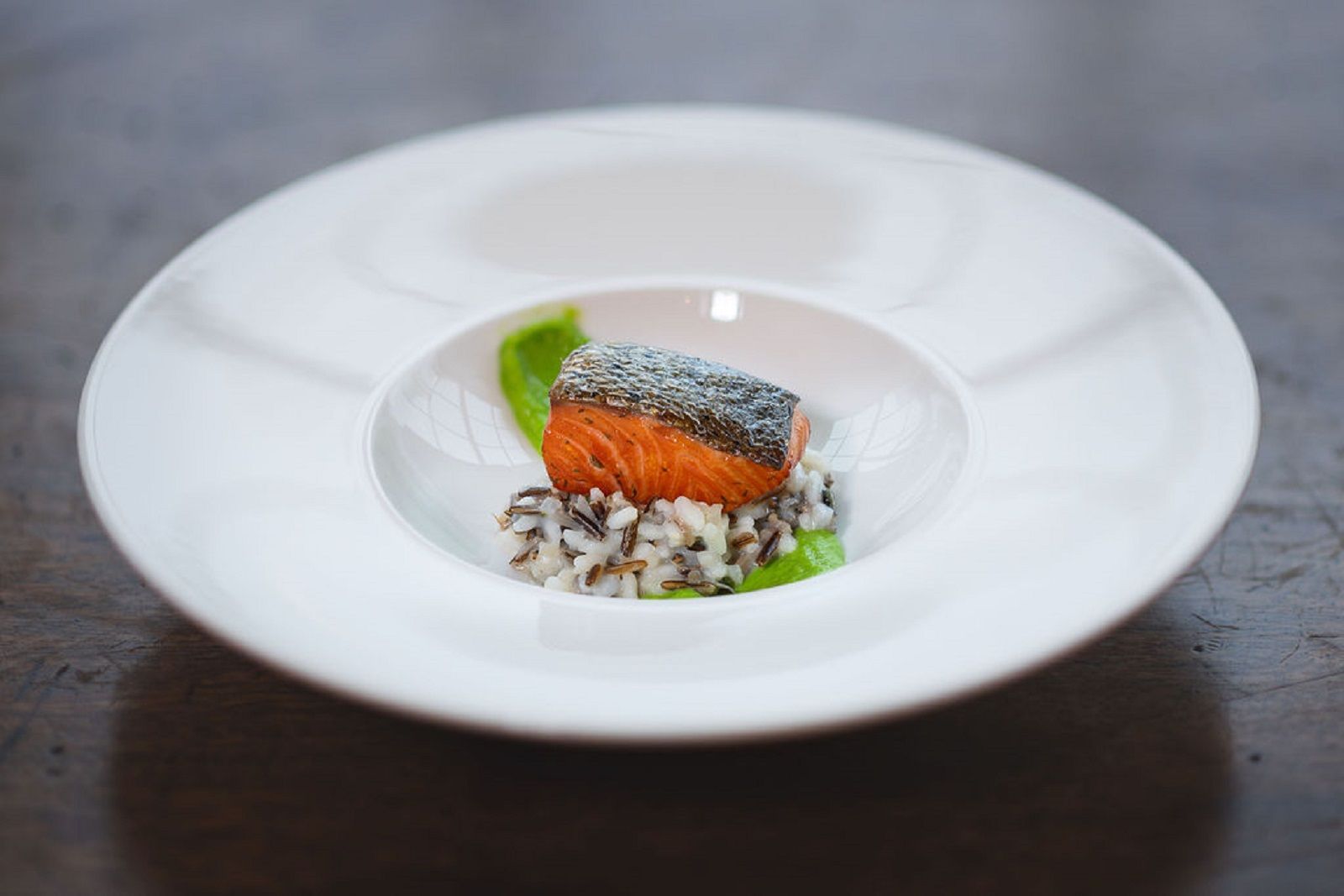 a white plate topped with a piece of salmon and rice on a table .