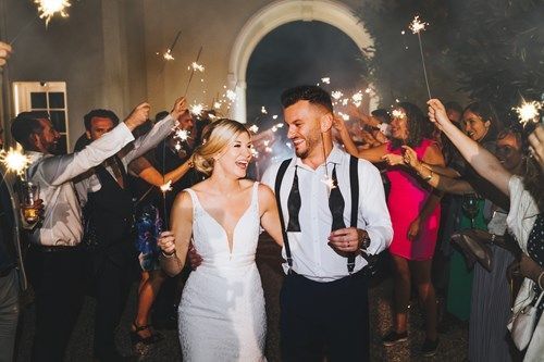 a bride and groom are walking through a crowd of people holding sparklers .
