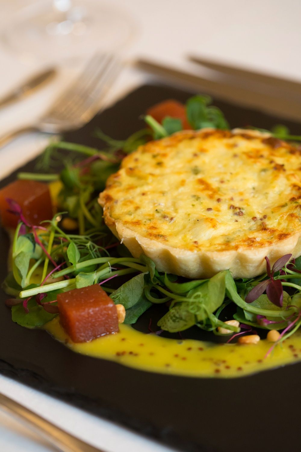 a close up of a plate of food with a quiche and salad on a table .