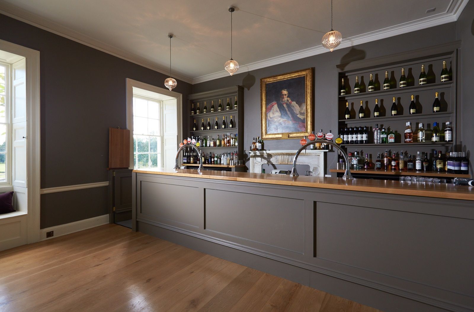 A bar with a lot of bottles on the shelves and a painting on the wall.