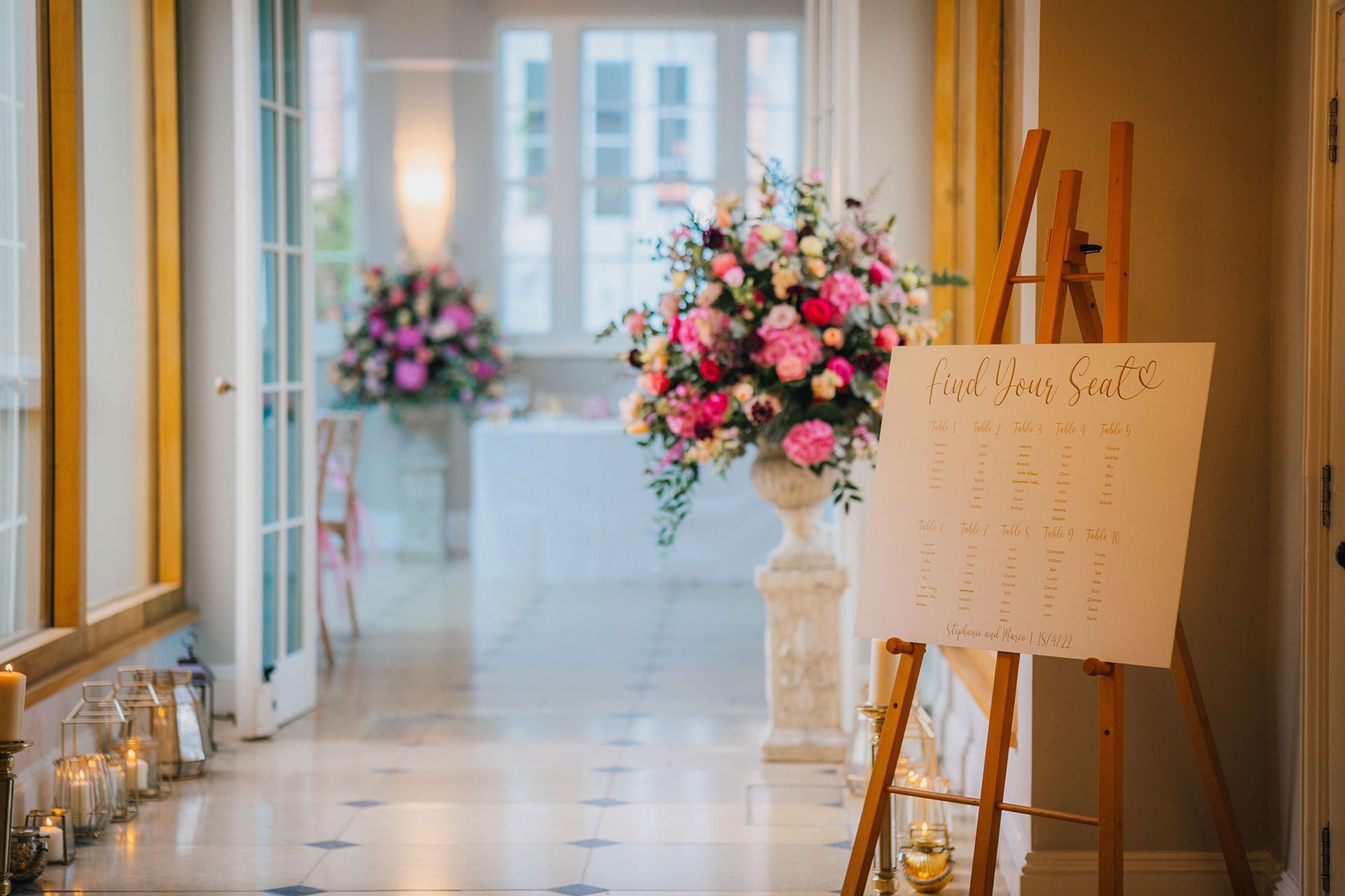 a hallway with a vase of pink flowers and a sign on an easel .