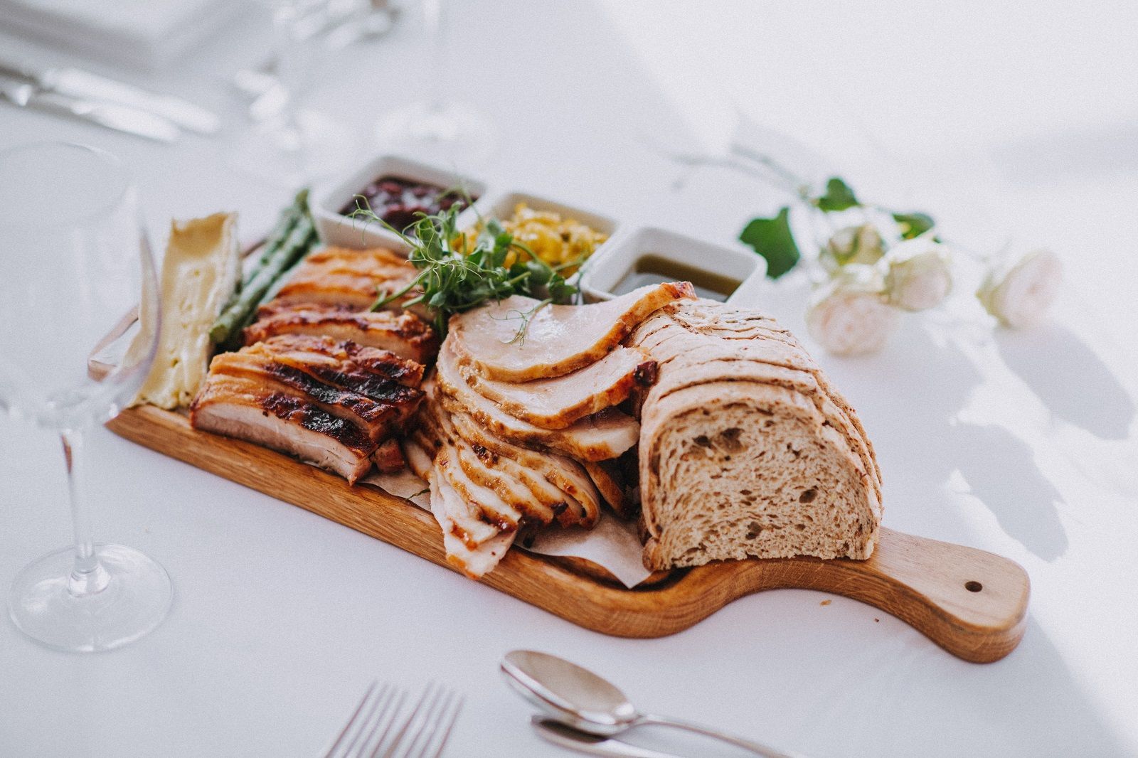a wooden cutting board topped with meat and bread on a table .