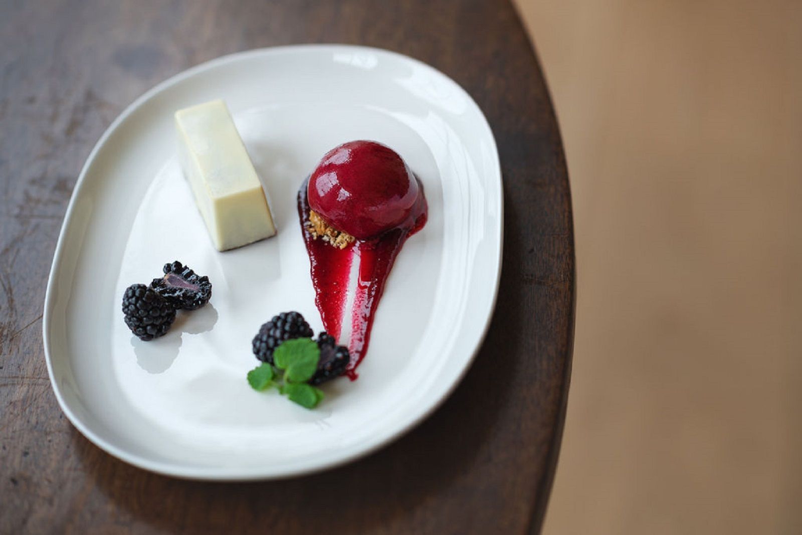 a white plate topped with a dessert and berries on a wooden table .