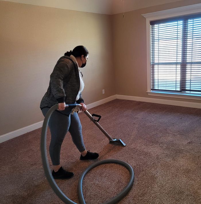 A woman is using a vacuum cleaner in an empty room