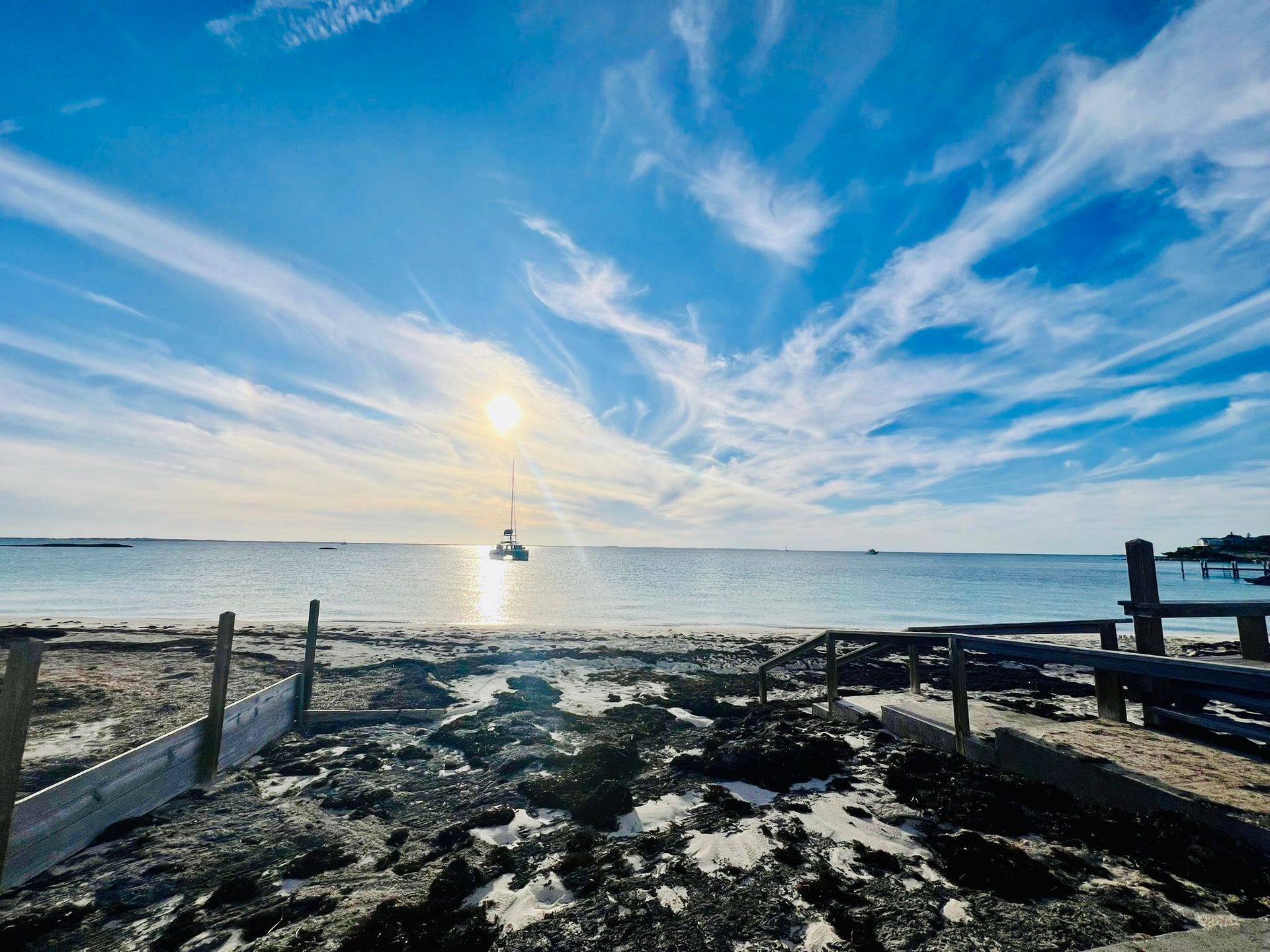 Beach with turquoise water, white sand, and a cloudy sky with patches of blue.