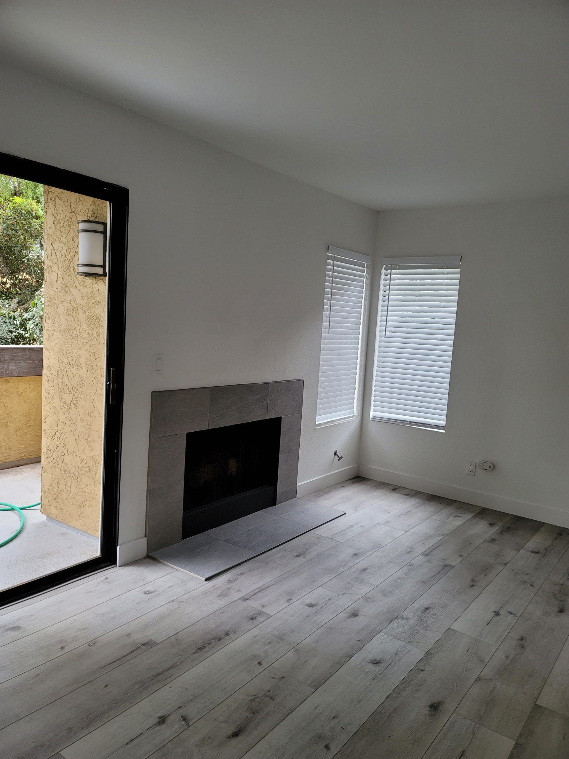 An empty living room with a fireplace and sliding glass doors.