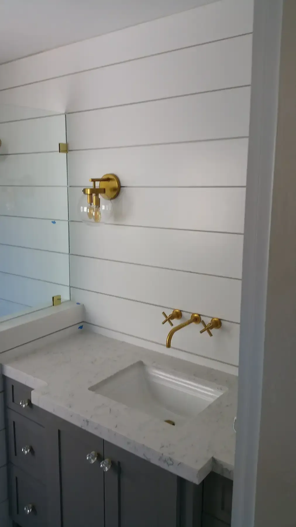 A bathroom with a sink , mirror and faucet. Bathroom remodel with gold accents in Point Loma