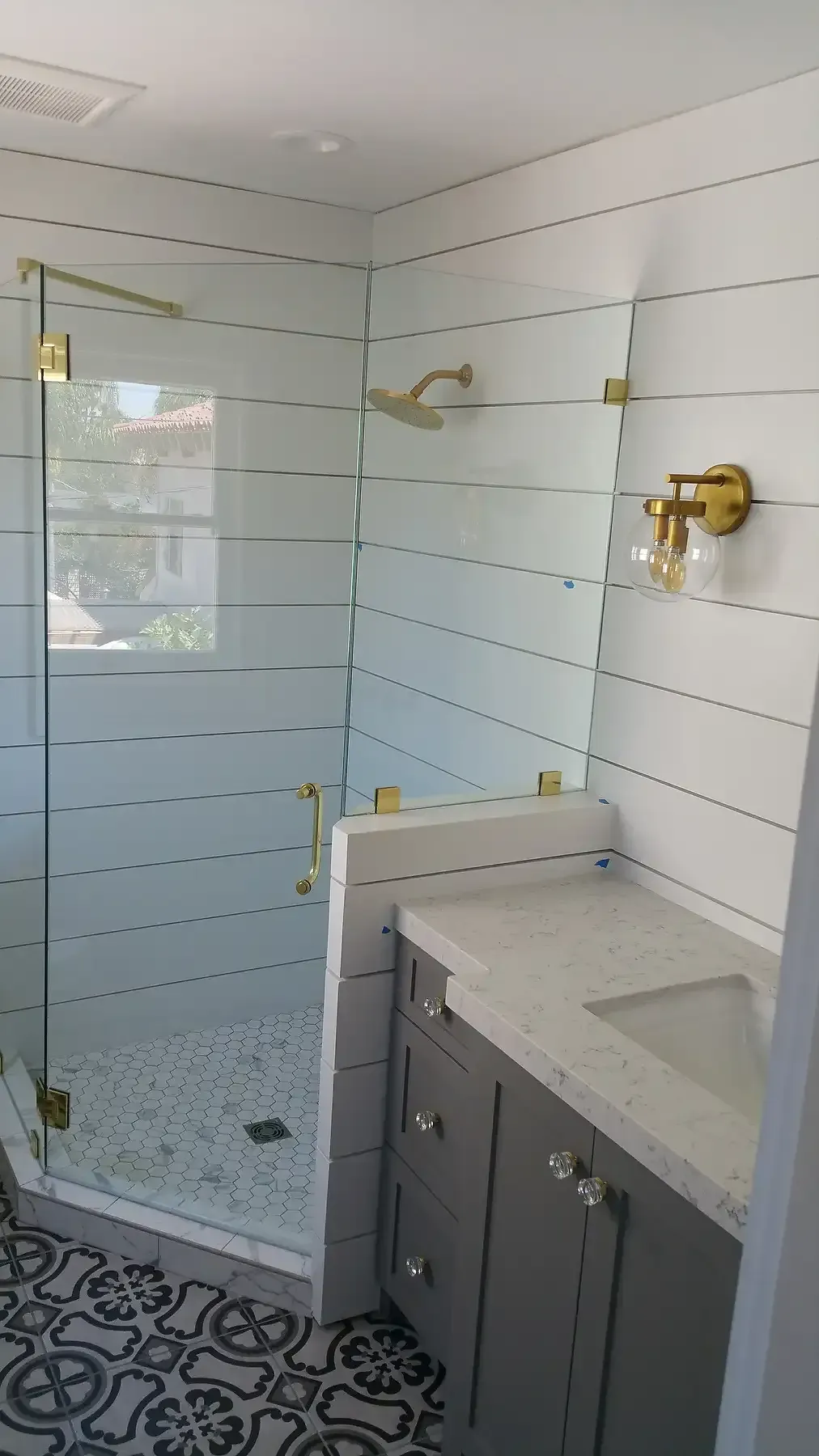 A bathroom with a walk in shower , sink and mirror. Bathroom remodel with gold accents in Point Loma