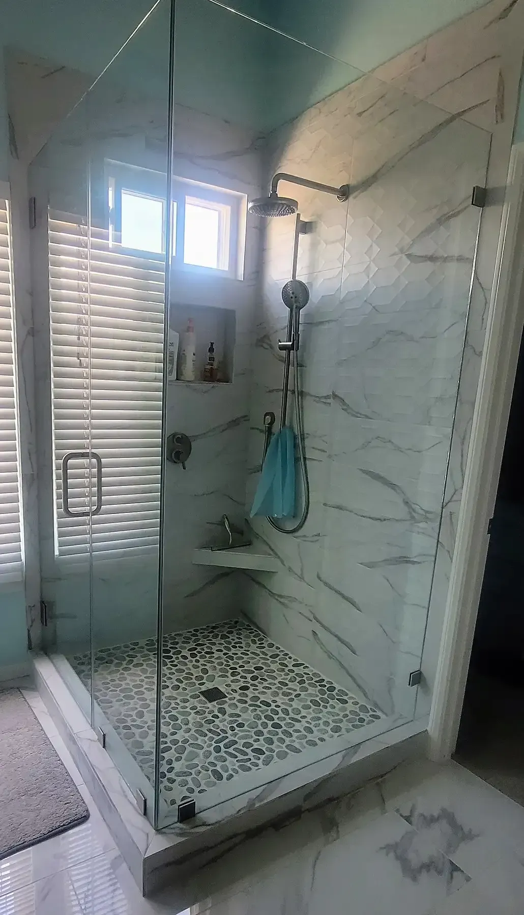 A bathroom with a walk in shower and a window.