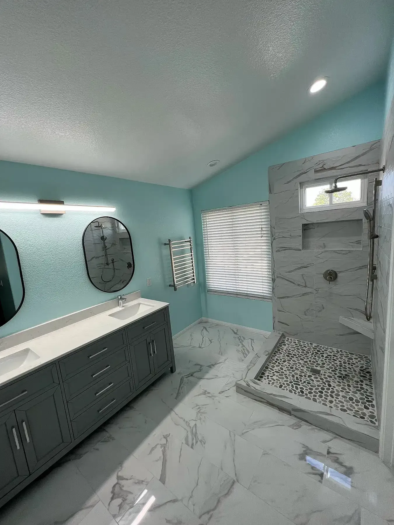 A bathroom with a walk in shower and two sinks.