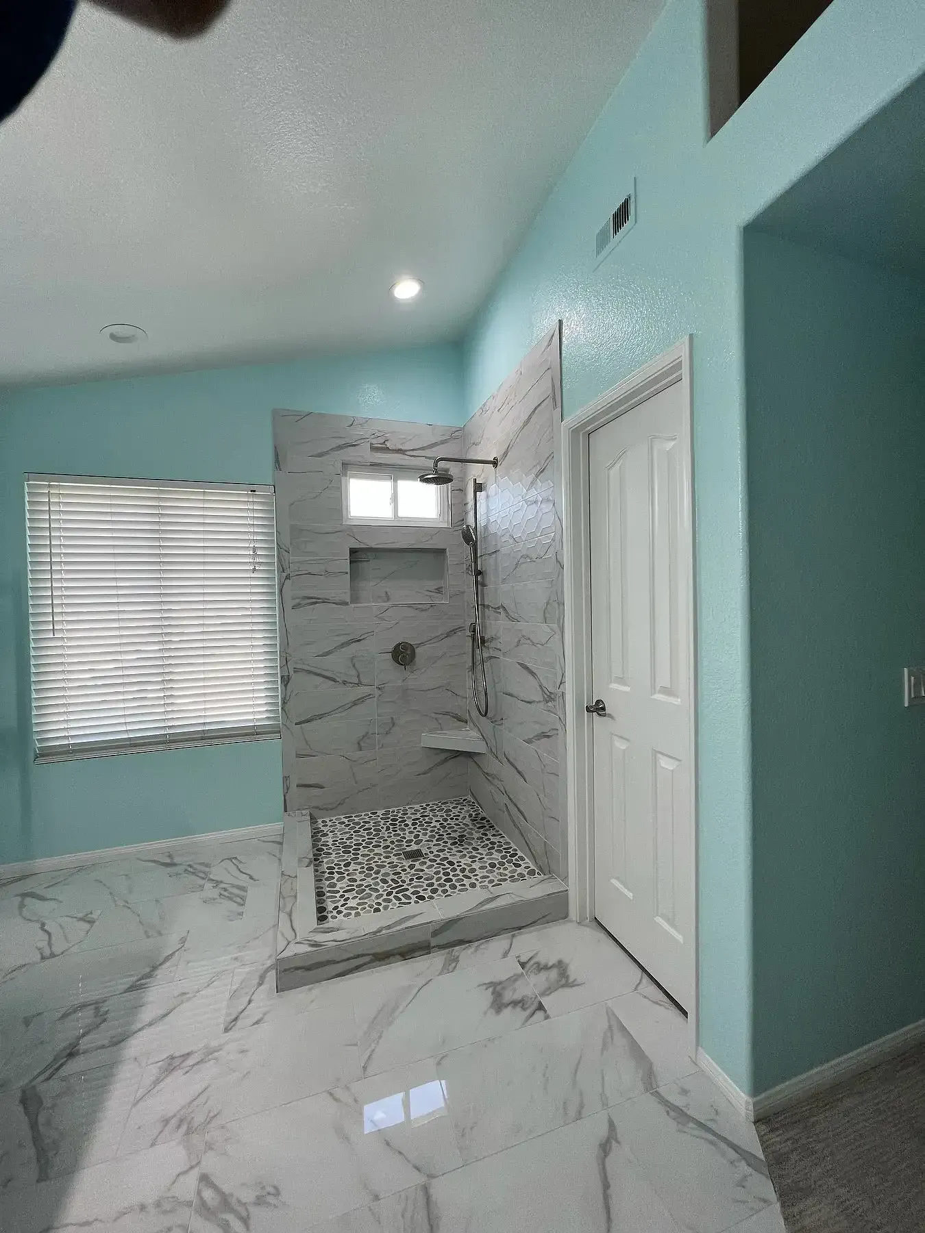 A bathroom with a walk in shower and a window.