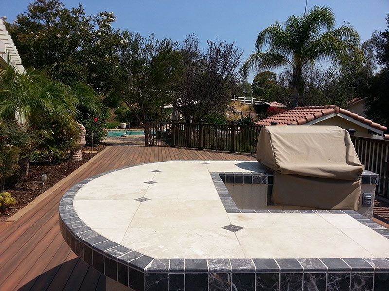 A wooden deck with a circular table and a grill