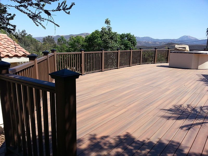 A wooden deck with a fence and mountains in the background