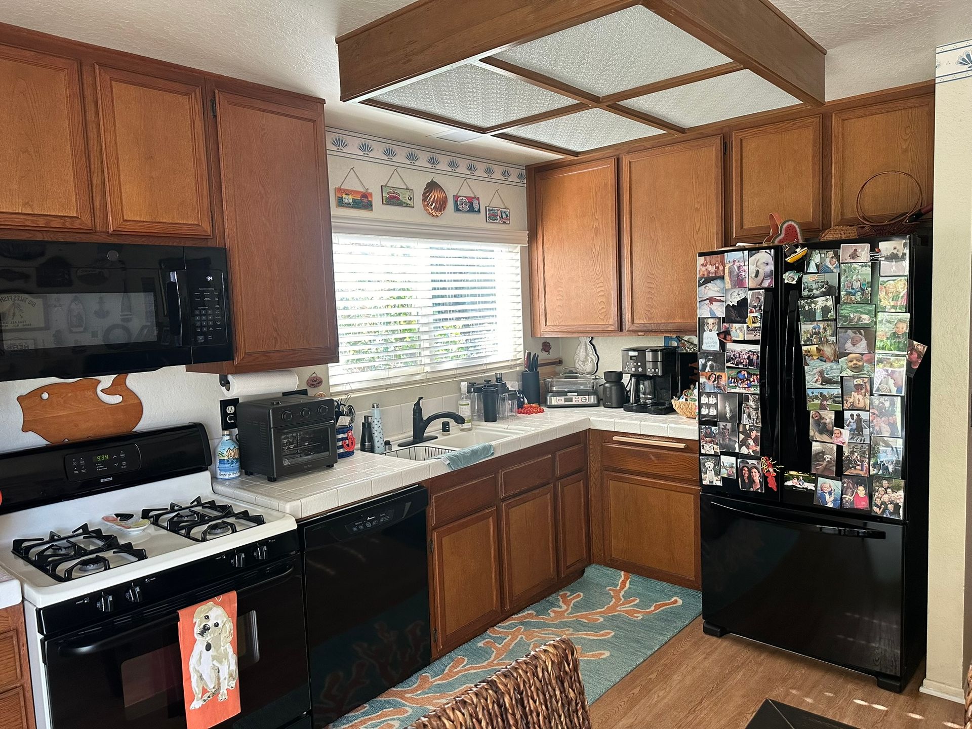 Team Renovate - A kitchen with brown cabinets, black appliances, and a window with blinds.