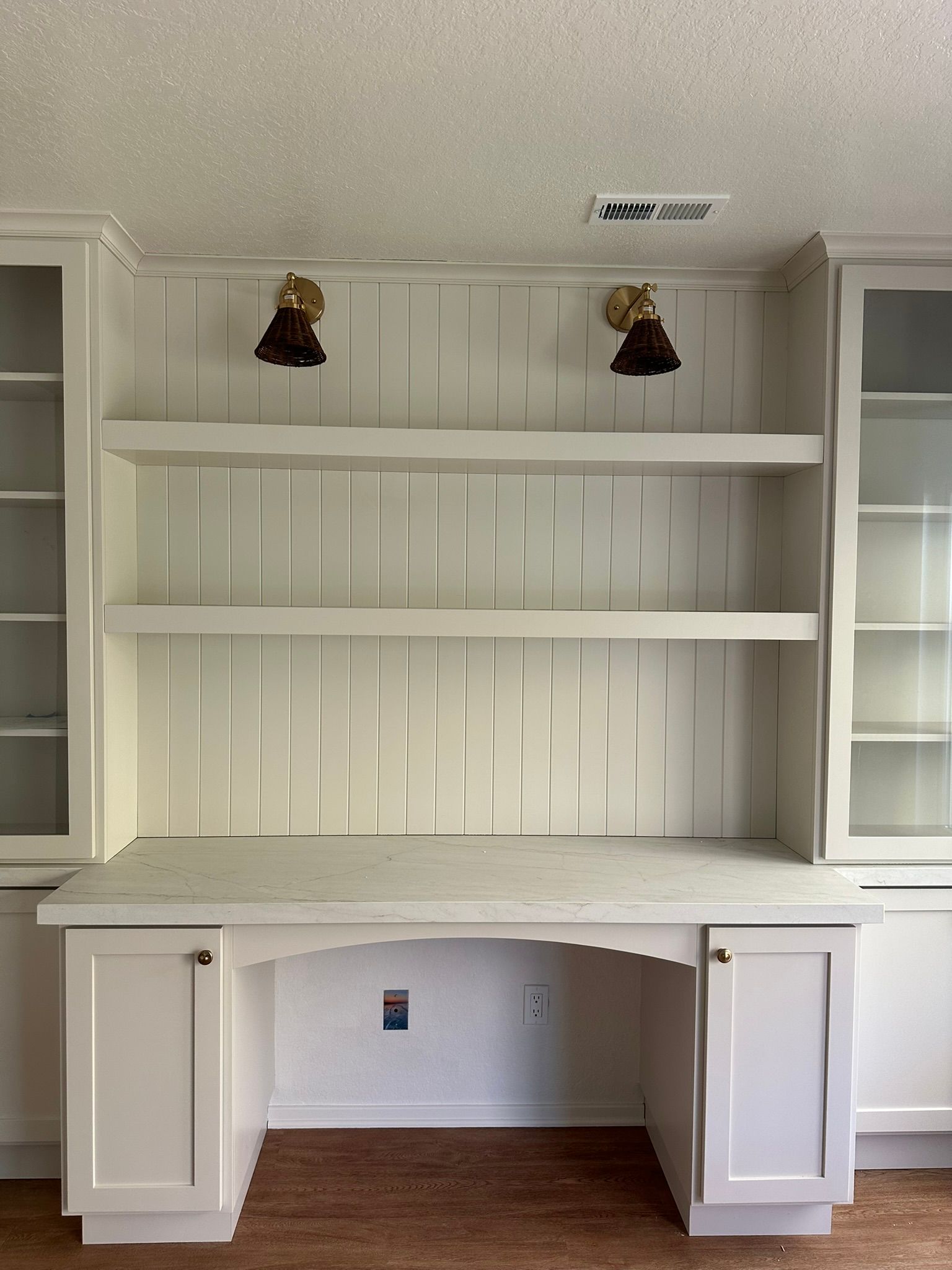 Team Renovate - White built-in desk with shelves, two wall sconces, and cabinets.