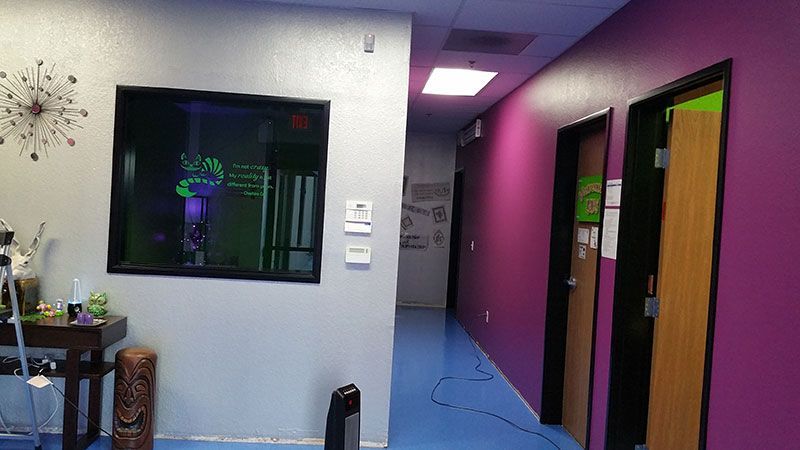 A hallway with purple walls and blue floors and a clock on the wall.