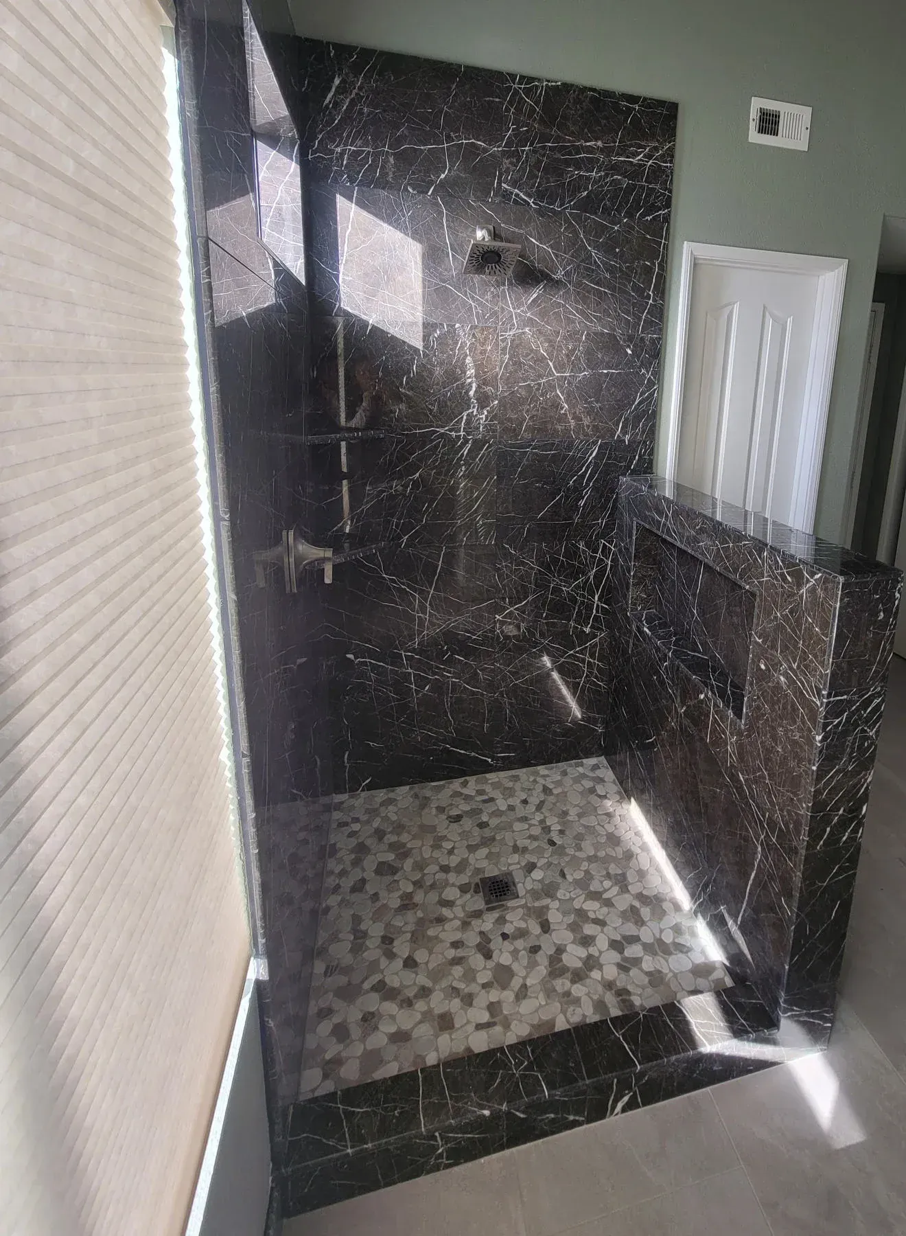 A bathroom with a walk in shower and a window from a Bathroom remodel in San Diego CA by Team  Renovate