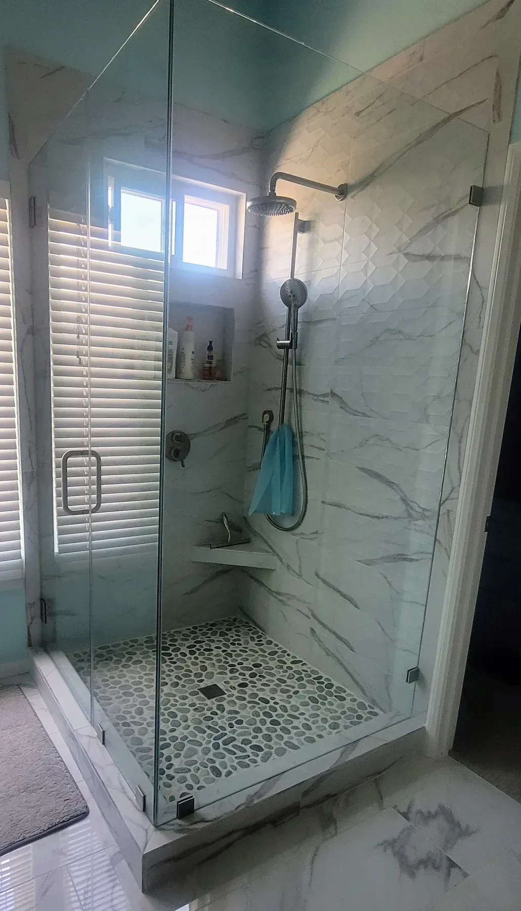 A bathroom with a walk in shower and a window from a Bathroom remodel in San Diego CA by Team  Renovate