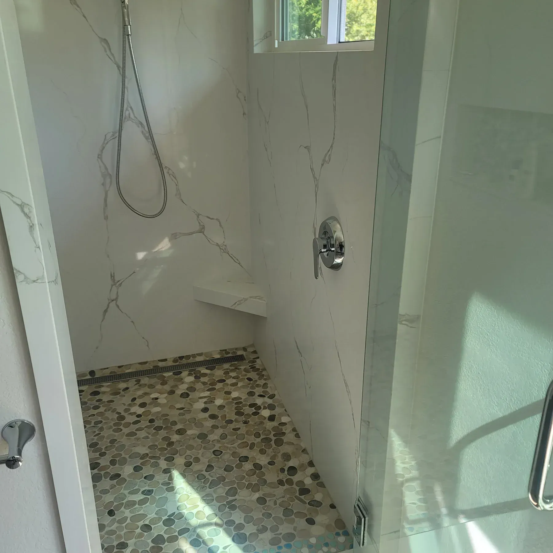 A bathroom with a walk in shower and a window from a Bathroom remodel in San Diego CA by Team  Renovate