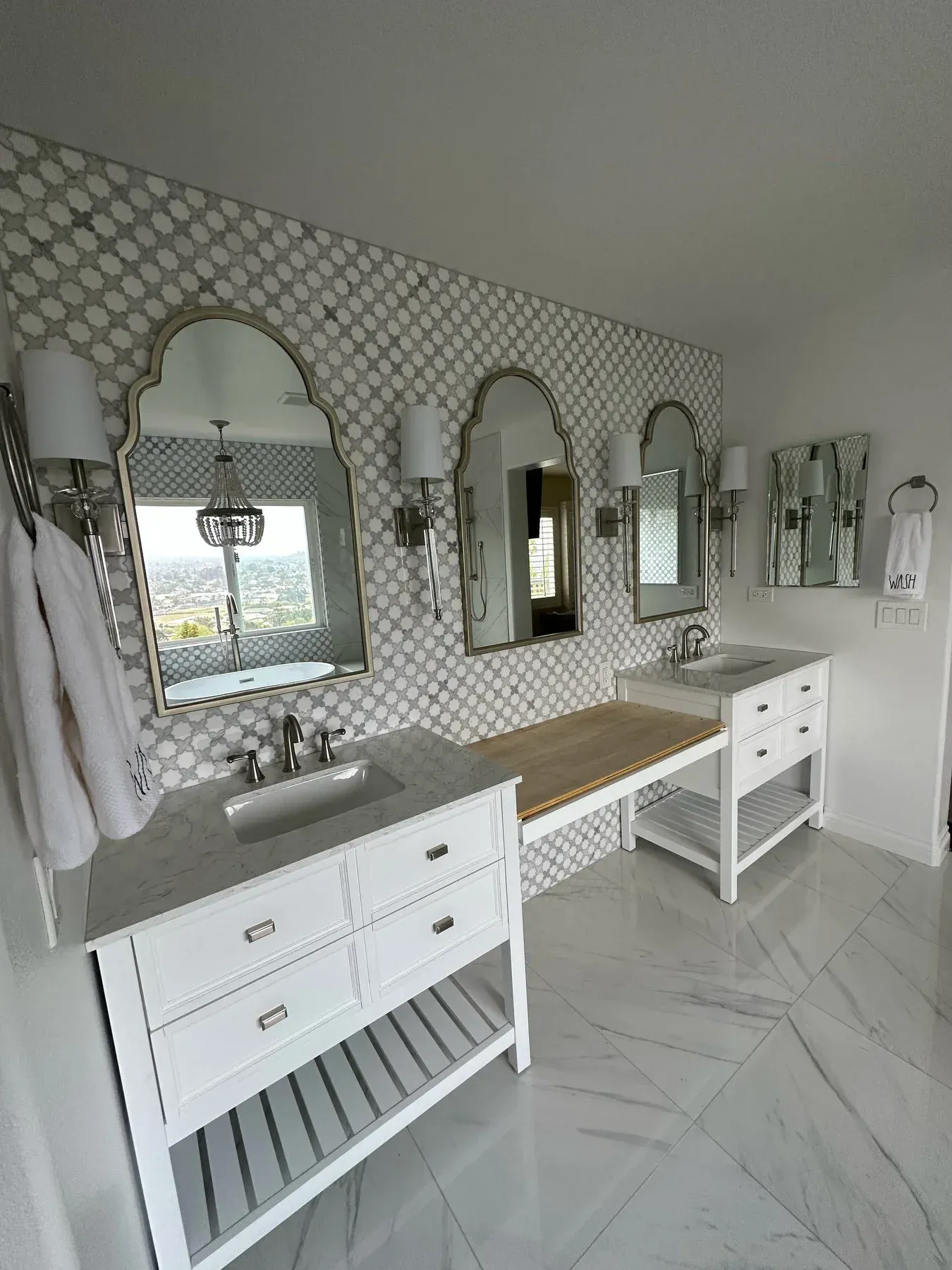 A bathroom with two sinks , two mirrors and a bench from a Bathroom remodel in San Diego CA by Team  Renovate