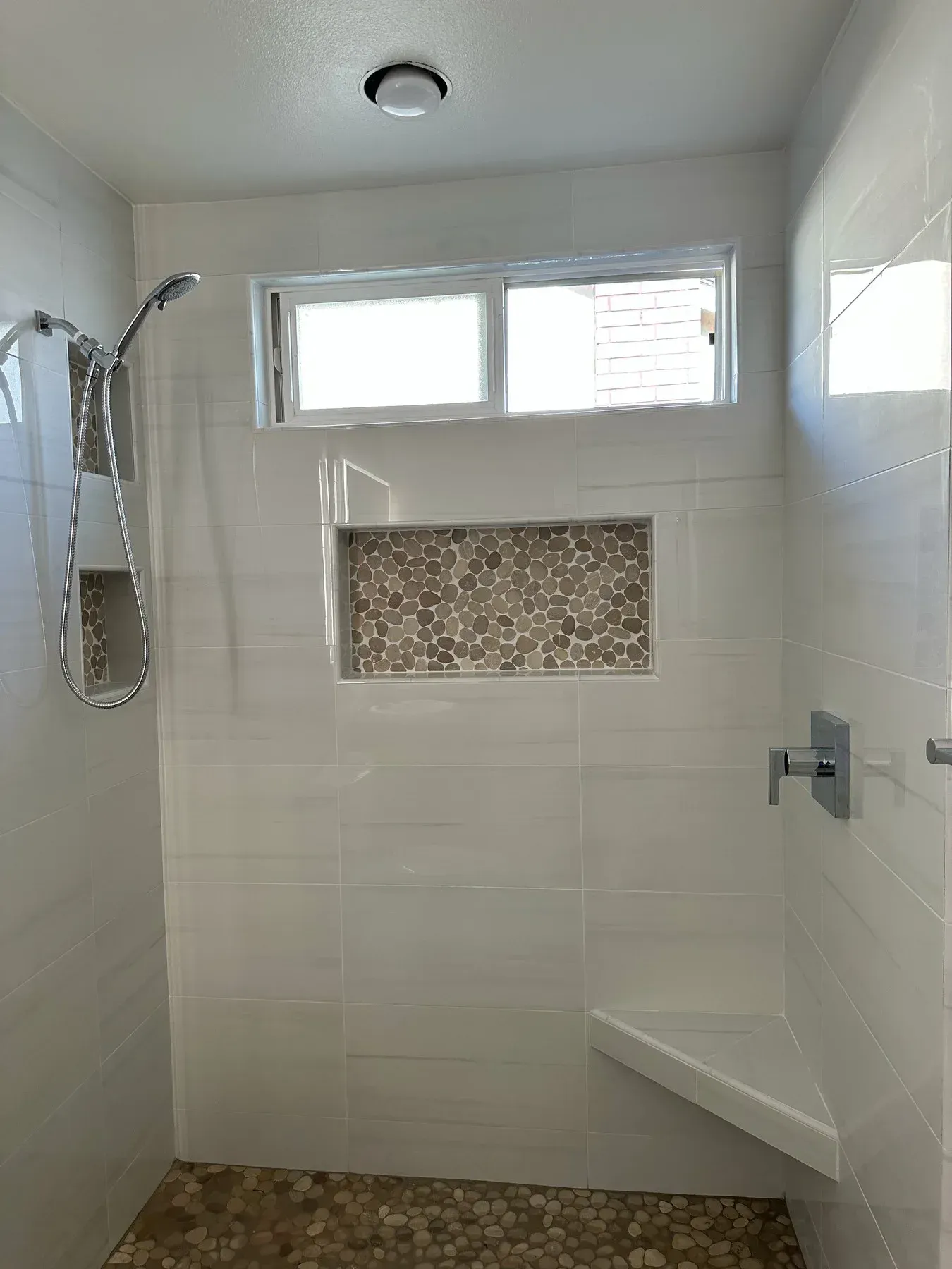 A walk in shower with a window and a bench from a Bathroom remodel in San Diego CA by Team  Renovate
