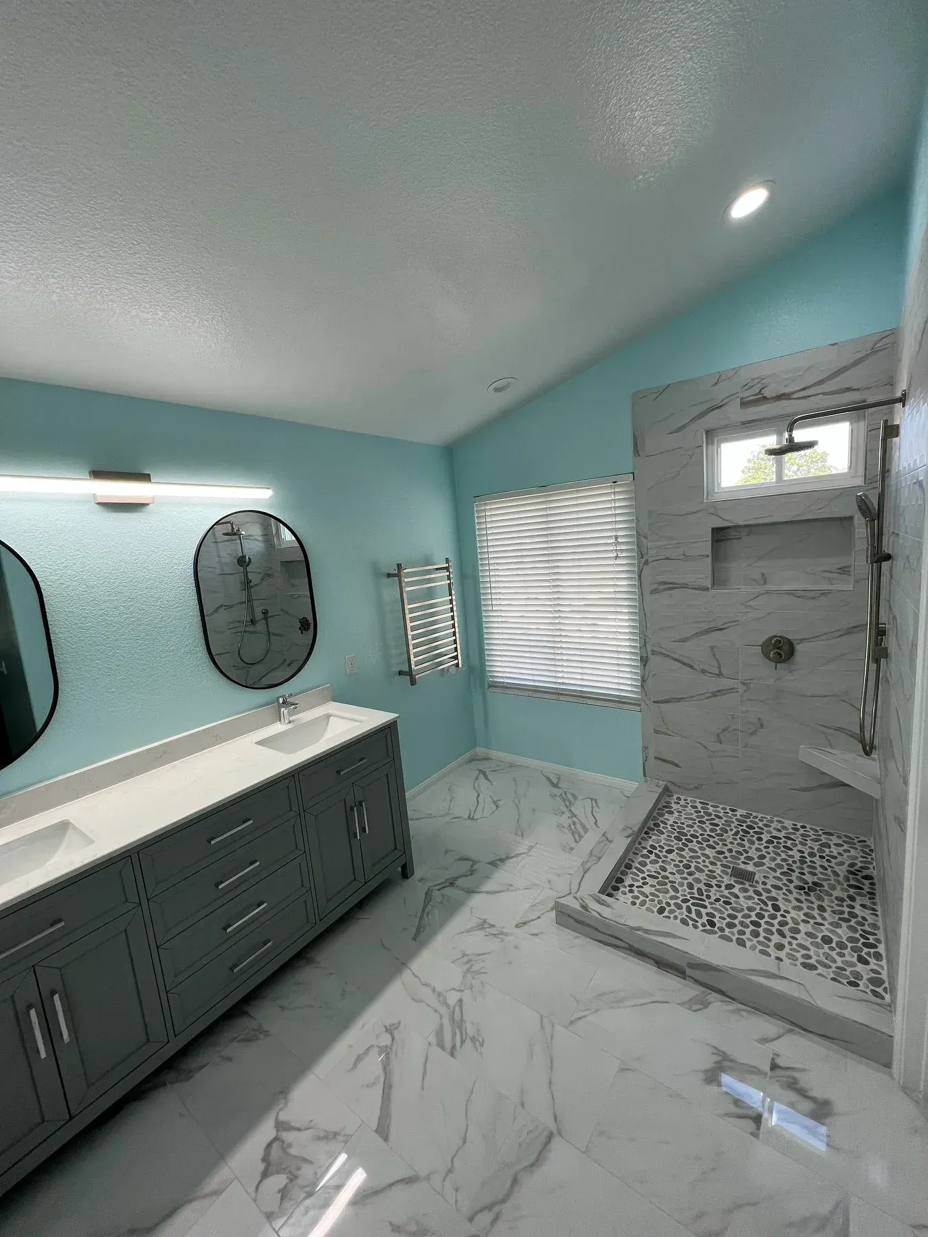 A bathroom with two sinks and a walk in shower from a Bathroom remodel in San Diego CA by Team  Renovate