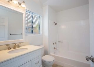 A bathroom with a toilet , sink , mirror and bathtub from a Bathroom remodel in San Diego CA by Team  Renovate